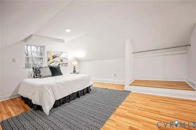 a view of a hallway with wooden floor and a bathroom