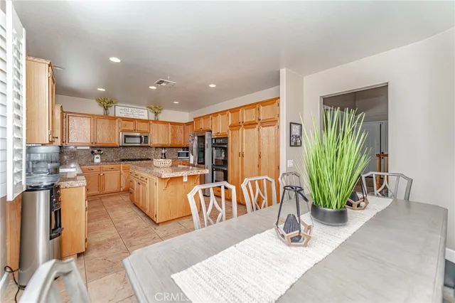 a kitchen with stainless steel appliances kitchen island granite countertop a refrigerator a stove and a sink with granite countertops