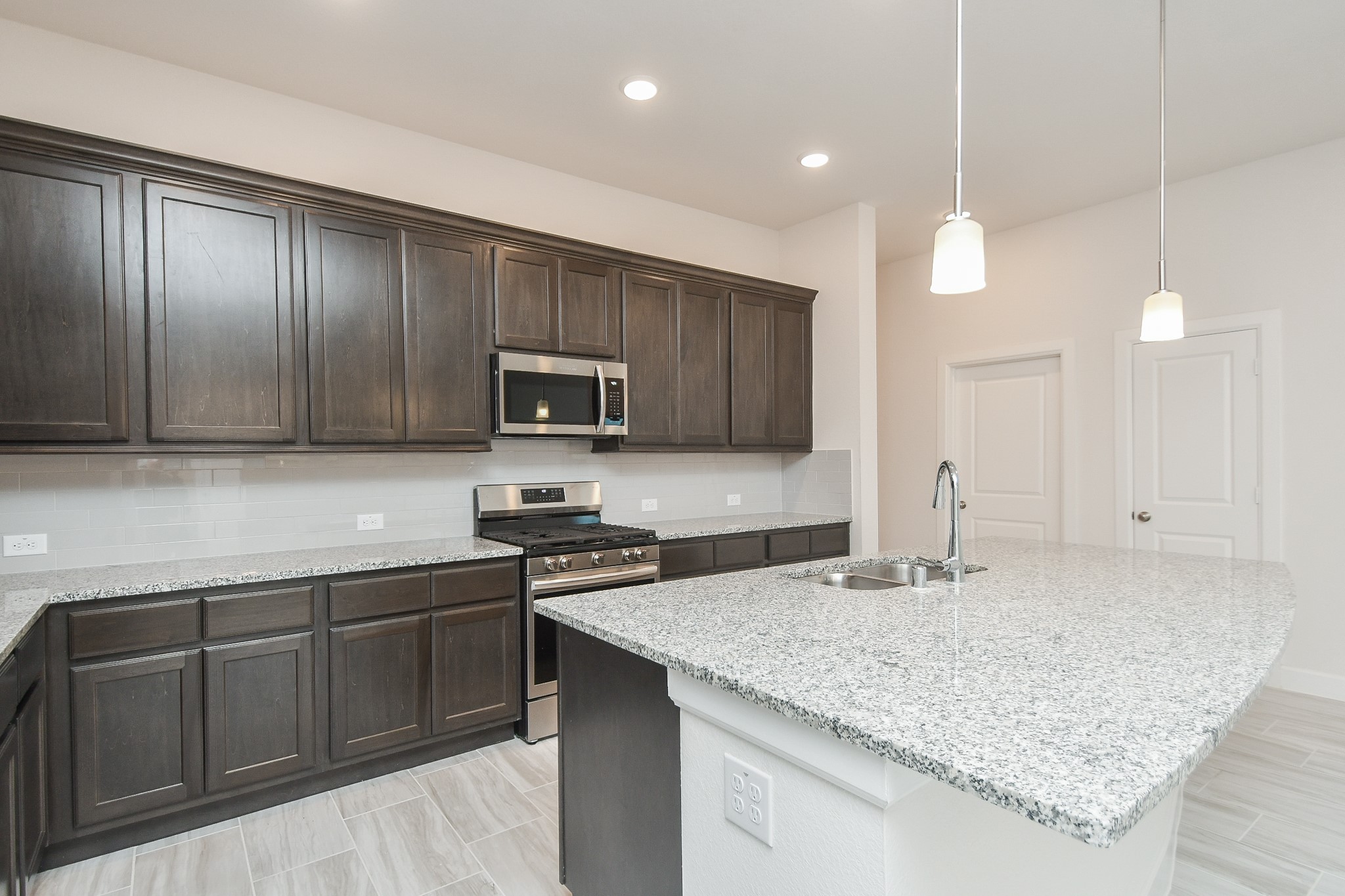 146 Amaranth Way Richmond, TX 77406 - Photo 5 of 18 a kitchen with kitchen island granite countertop stainless steel appliances a sink stove and microwave