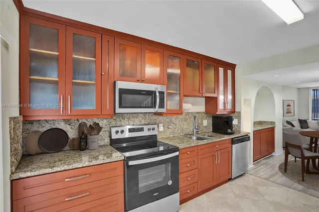 a kitchen with granite countertop wooden cabinets stainless steel appliances and a sink