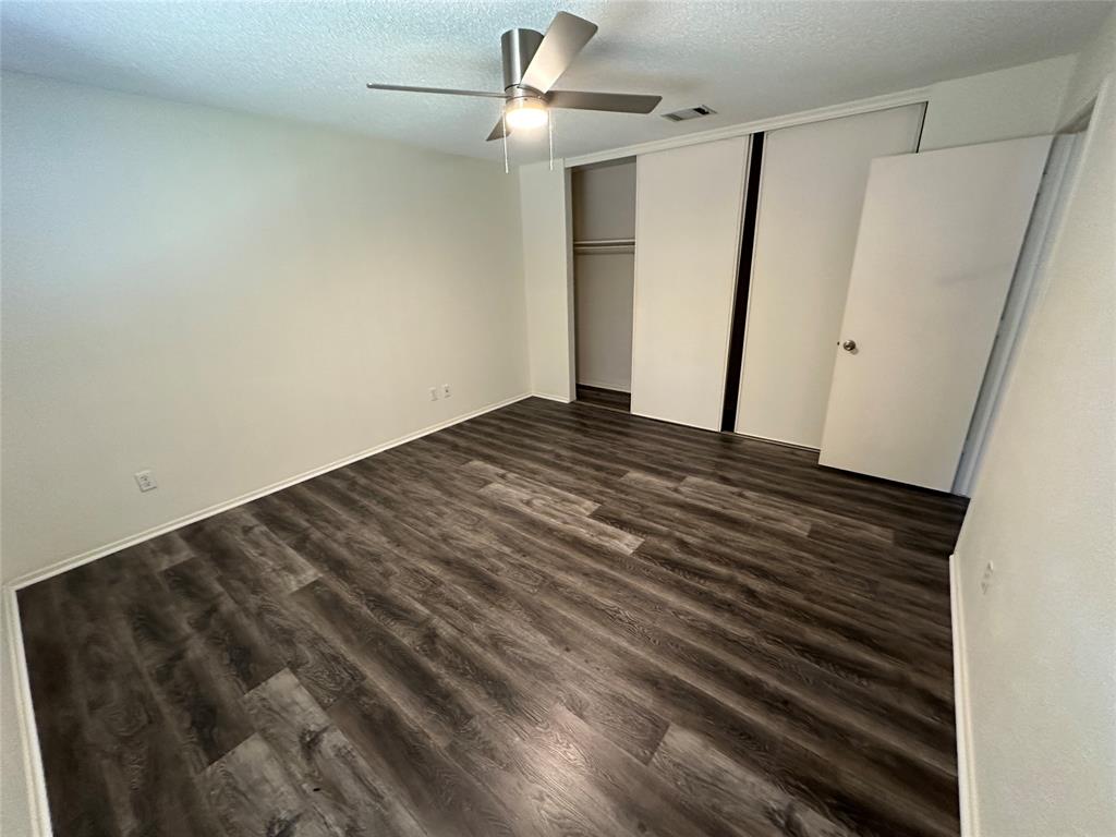 307 Harrington Lane Euless, TX 76039 - Photo 18 of 20 Unfurnished bedroom with dark wood-style flooring, a textured ceiling, a ceiling fan, and a closet