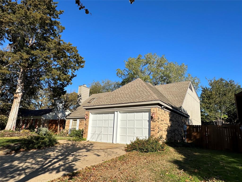 307 Harrington Lane Euless, TX 76039 - Photo 2 of 20 View of side of property featuring brick siding, driveway, a chimney, an attached garage, and roof with shingles