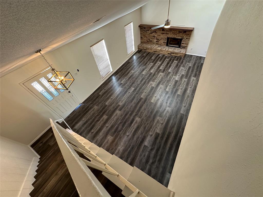 307 Harrington Lane Euless, TX 76039 - Photo 3 of 20 Stairs featuring a textured ceiling, wood finished floors, a fireplace, a ceiling fan, and a chandelier