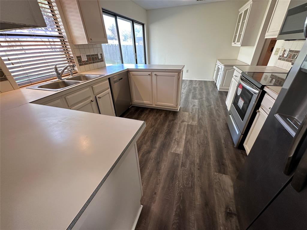 307 Harrington Lane Euless, TX 76039 - Photo 8 of 20 Kitchen with tasteful backsplash, light countertops, stainless steel appliances, and dark wood finished floors