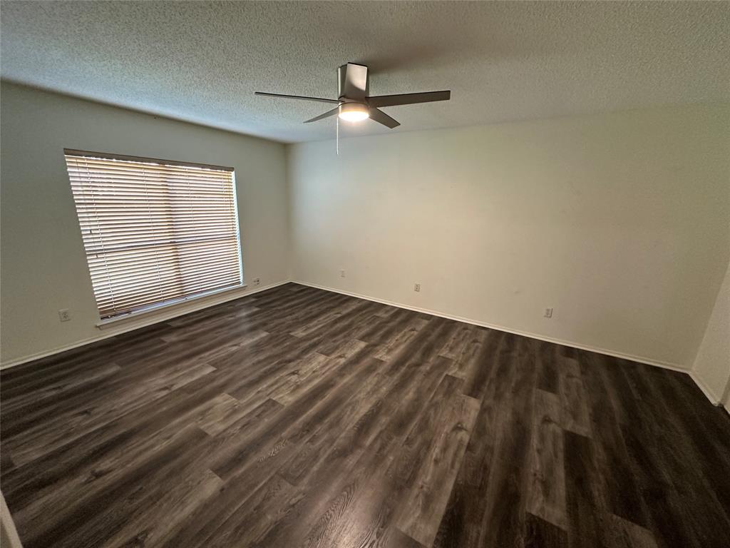 307 Harrington Lane Euless, TX 76039 - Photo 10 of 20 Empty room featuring dark wood-type flooring, a textured ceiling, and a ceiling fan