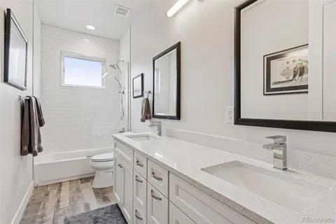 a bathroom with a double vanity sink a toilet a mirror and shower