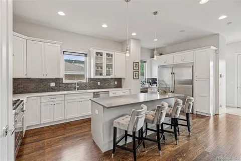 a kitchen with stainless steel appliances granite countertop a table chairs sink refrigerator and cabinets
