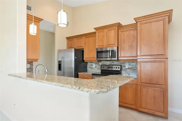 a kitchen with stainless steel appliances granite countertop a refrigerator a stove and a sink with wooden floor