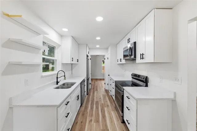 a kitchen with stainless steel appliances a sink a stove a refrigerator cabinets and a dining table