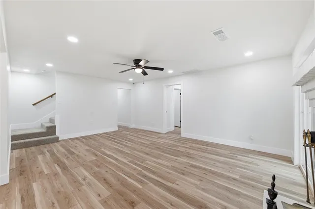 an empty room with wooden floor fan and windows