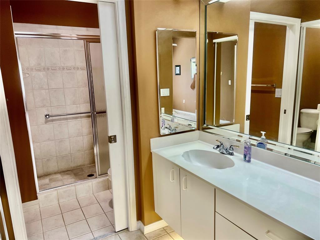 9539 Weldon Circle, Unit F406 Tamarac, FL 33321 - Photo 11 of 22 a bathroom with a granite countertop sink a mirror and shower