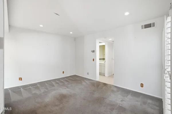 an empty room with a bathroom and mirror