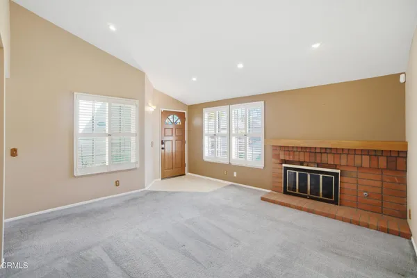 a view of an empty room with a fireplace and a window