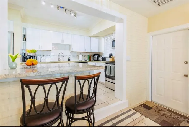 a kitchen with stainless steel appliances granite countertop a refrigerator a stove and a sink with wooden floor