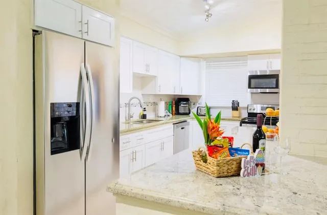 a kitchen with stainless steel appliances granite countertop a stove top oven a dining table and chairs with white cabinets