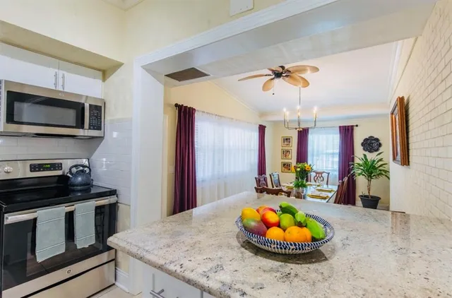 a kitchen with stainless steel appliances granite countertop a refrigerator a stove a sink dishwasher and white cabinets with wooden floor