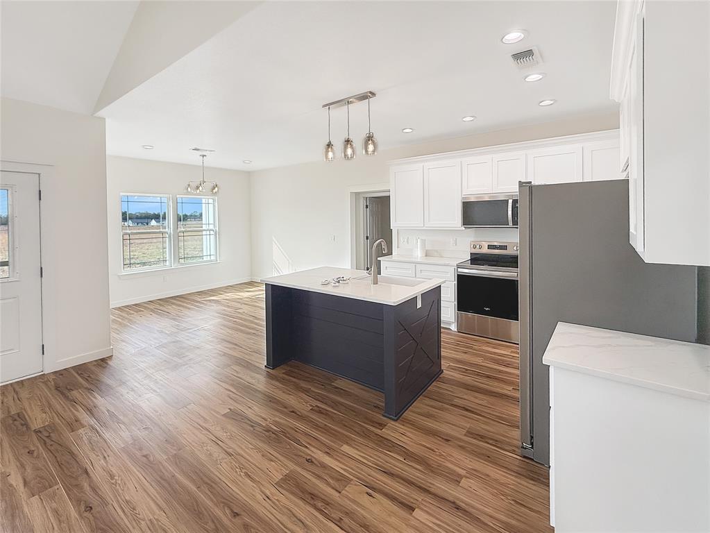 6472 Old Clarksville Road Reno, TX 75462 - Photo 4 of 22 a large kitchen with stainless steel appliances kitchen island a large counter top and a wooden floor