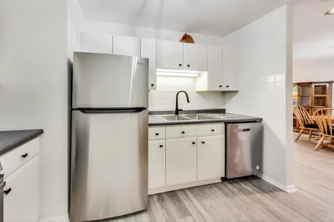 a kitchen with granite countertop white cabinets and white appliances