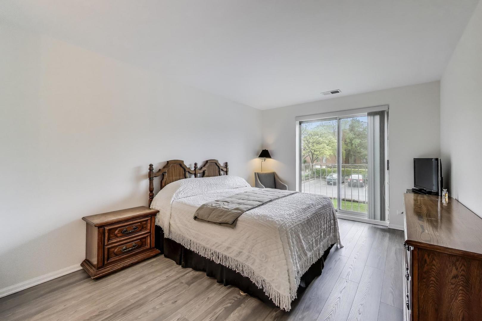 805 Leicester Road, Unit B105 Elk Grove Village, IL 60007 - Photo 12 of 37 a bedroom with a bed and a flat screen tv