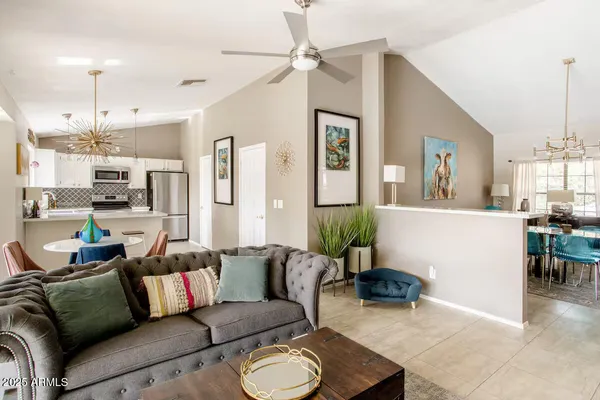 a living room with furniture kitchen view and a chandelier