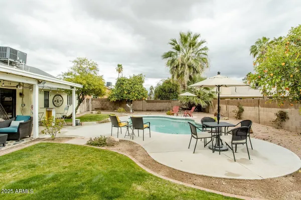 a view of a swimming pool with table and chairs under an umbrella