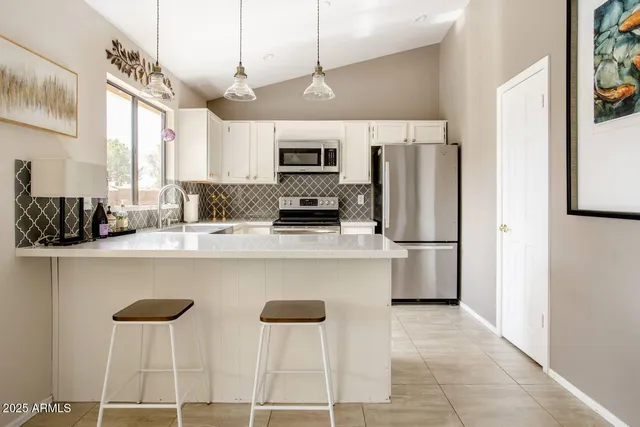 a kitchen with stainless steel appliances a refrigerator a sink a stove a microwave a dining table and chairs