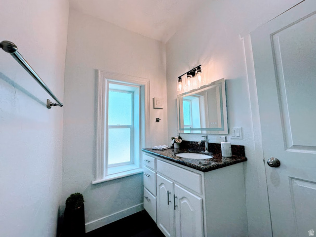 629 North 100 East Logan, UT 84321 - Photo 8 of 11 Bathroom featuring a white vanity with panel cabinetry and silver hardware, a speckled granite countertop, and an undermount sink with a chrome faucet