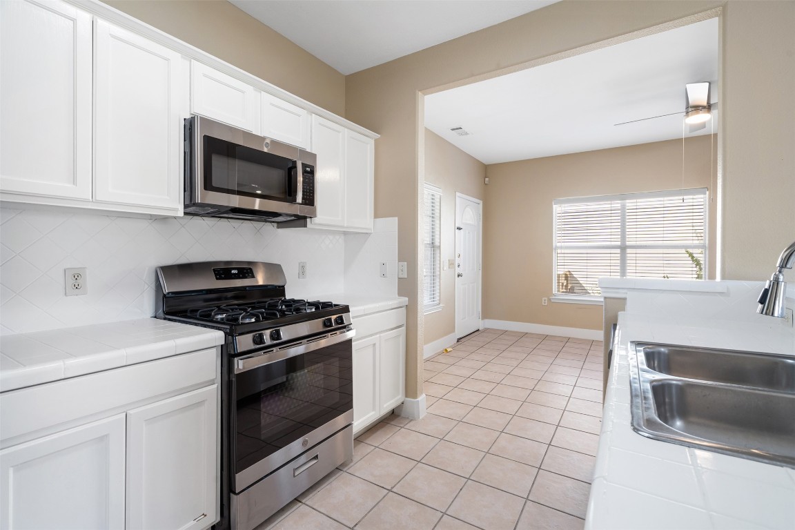 5909 Signal Point Austin, TX 78724 - Photo 10 of 32 a kitchen with stainless steel appliances a stove a microwave and white cabinets