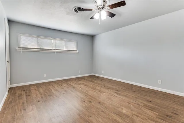 an empty room with chandelier fan and windows
