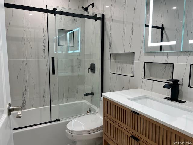 228 Springmeadow Drive, Unit H Holbrook, NY 11741 - Photo 7 of 12 Bathroom featuring vanity, bath / shower combo with glass door, and tile walls