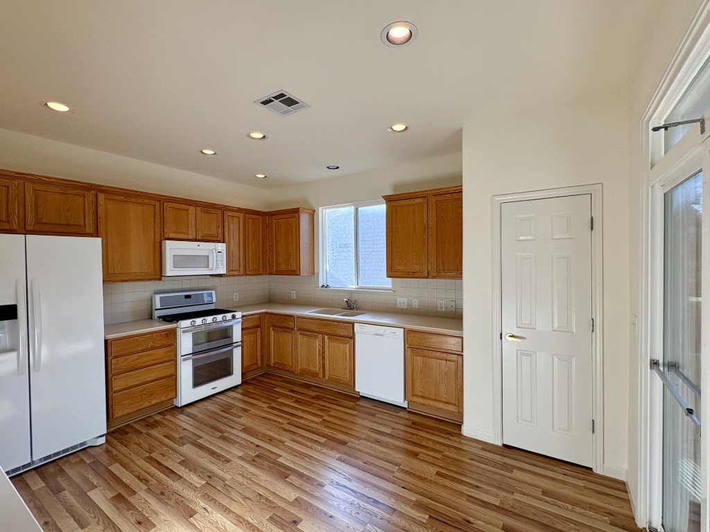 106 Prospector Pass Georgetown, TX 78633 - Photo 5 of 14 a kitchen with stainless steel appliances granite countertop a refrigerator a sink dishwasher a stove and white countertops with wooden floor