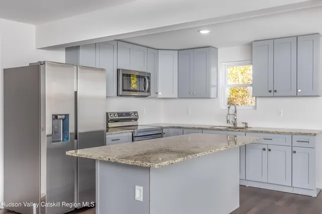 a kitchen with stainless steel appliances granite countertop a sink and a refrigerator