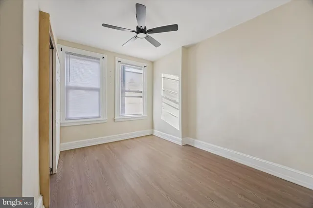 an empty room with wooden floor fan and windows