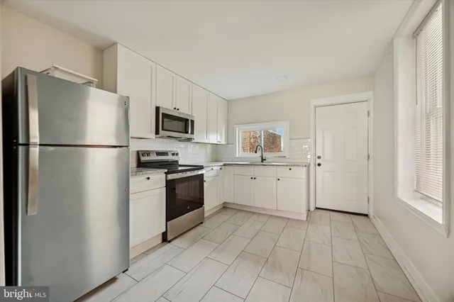 a kitchen with a refrigerator a stove top oven and white cabinets