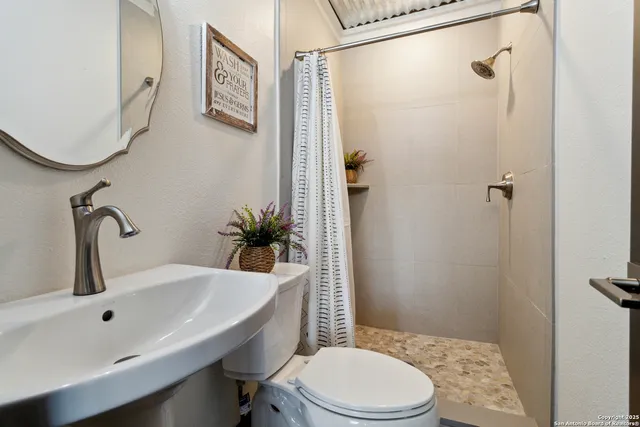 a bathroom with a granite countertop sink toilet and shower a mirror