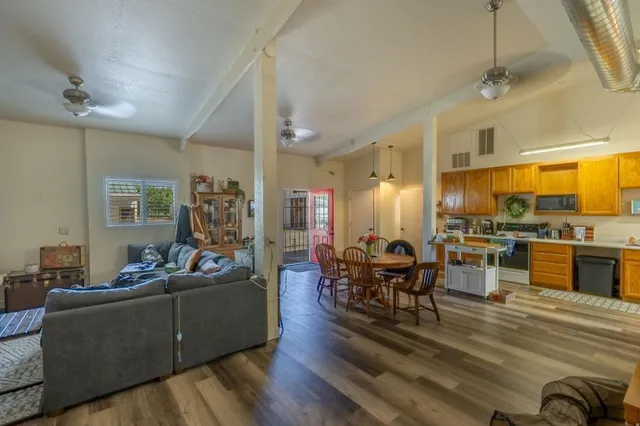 a living room with furniture kitchen view and a wooden floor
