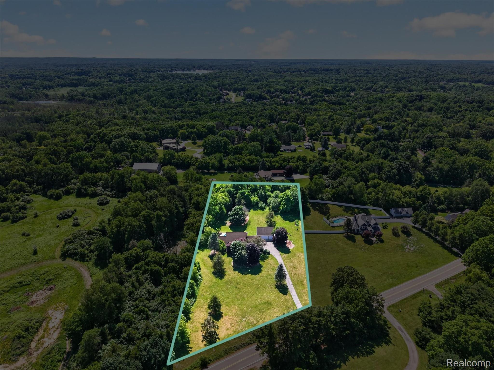 8114 Chilson Road Pinckney, MI 48169 - Photo 28 of 32 Aerial property overview featuring a single-family home with a long driveway, surrounded by mature trees and expansive green space