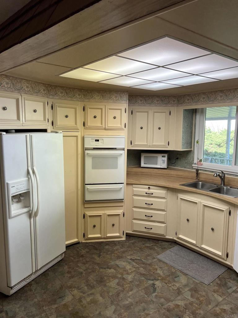 18218 Paradise Mountain Road, Unit SPACE 83 Valley Center, CA 92082 - Photo 21 of 50 a kitchen with white cabinets and stainless steel appliances