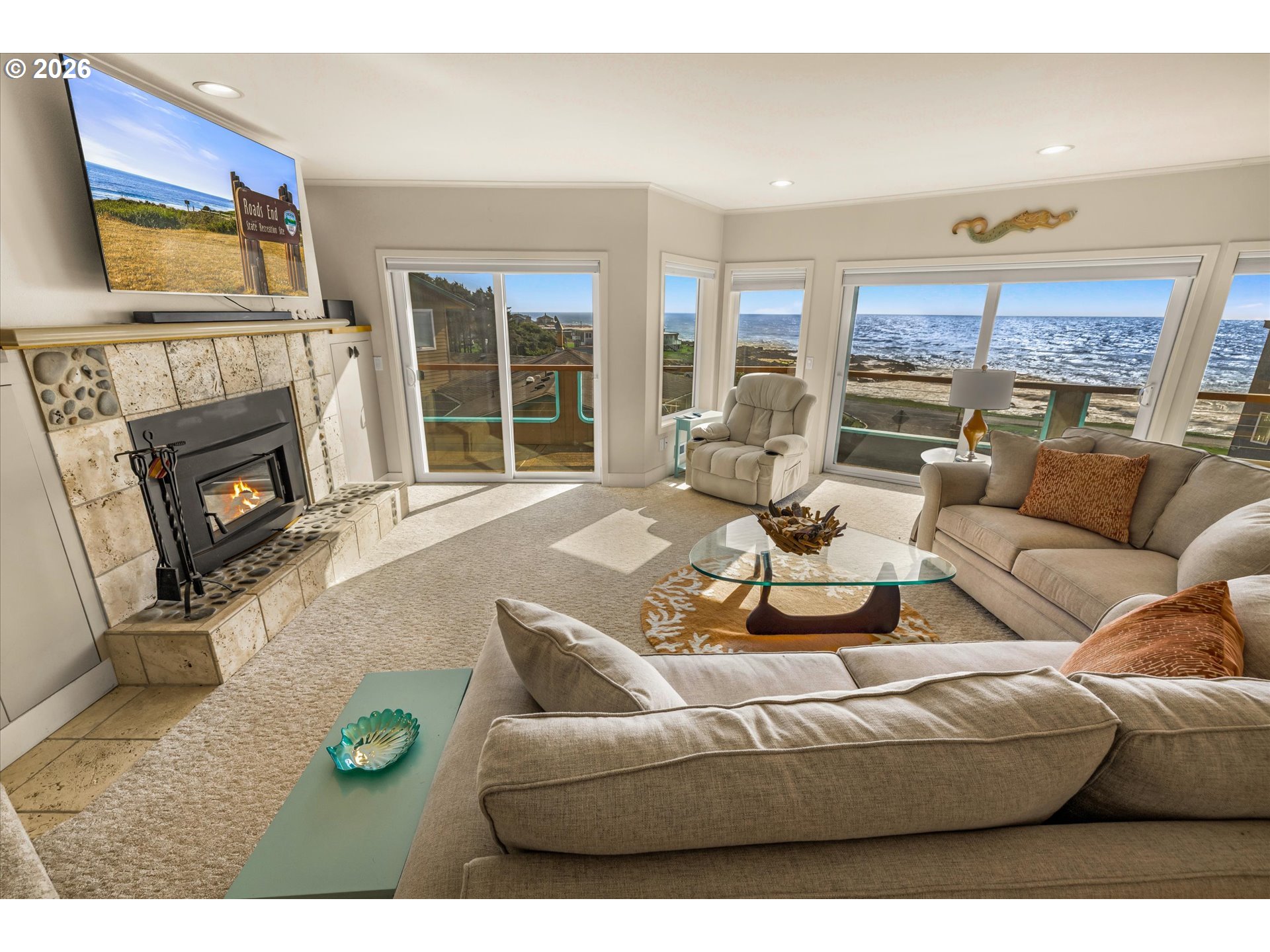 438 Shellmidden Way Yachats, OR 97498 - Photo 2 of 40 a living room with furniture a fireplace a flat screen tv and a large window
