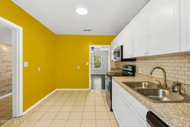 an empty room with wooden floor and windows with curtains