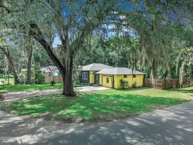 a view of a house with a yard and large trees