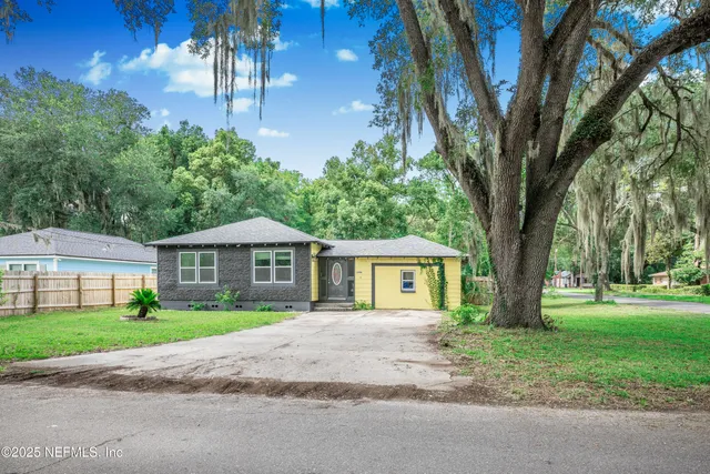 a front view of a house with a garden and trees