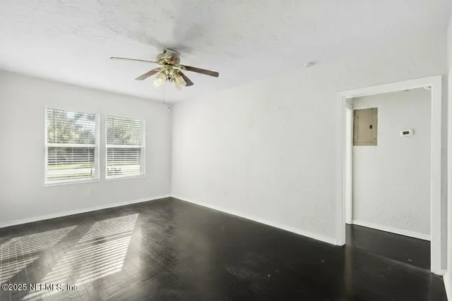 a view of an empty room with wooden floor and a window