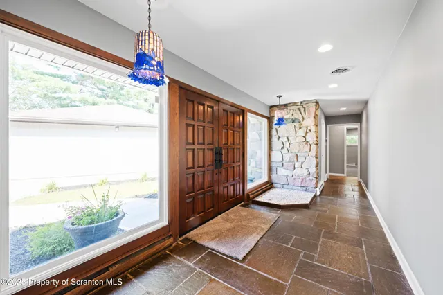 a view of an empty room with window and wooden floor