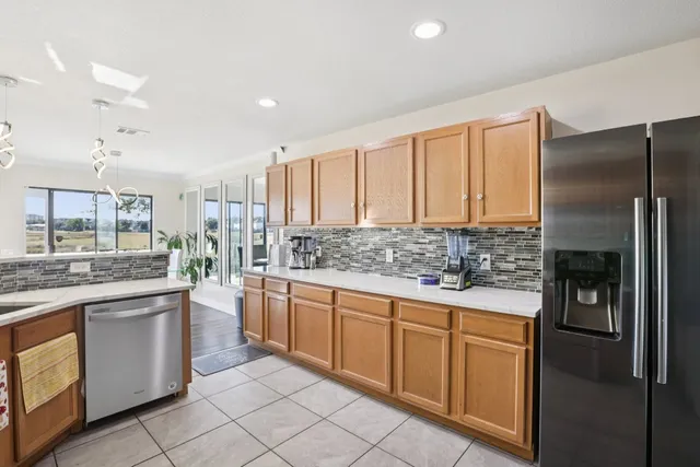 a kitchen with stainless steel appliances a sink a stove a refrigerator cabinets and a window