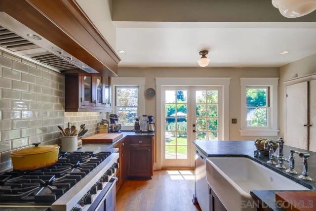 a kitchen with stainless steel appliances granite countertop a stove a sink dishwasher a dining table and chair with wooden floor