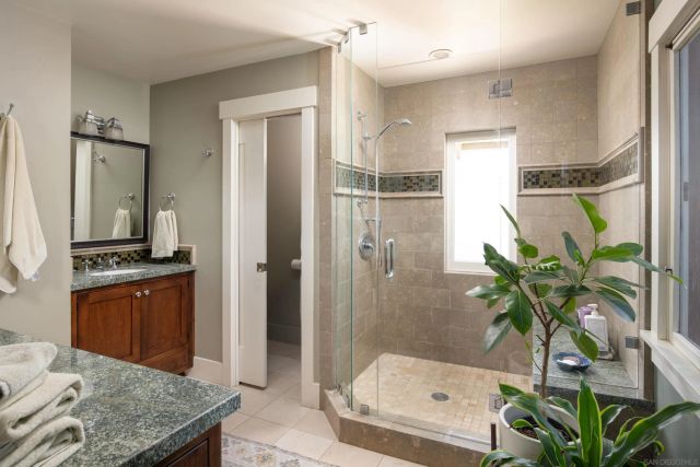 a bathroom with a granite countertop shower a sink and a mirror
