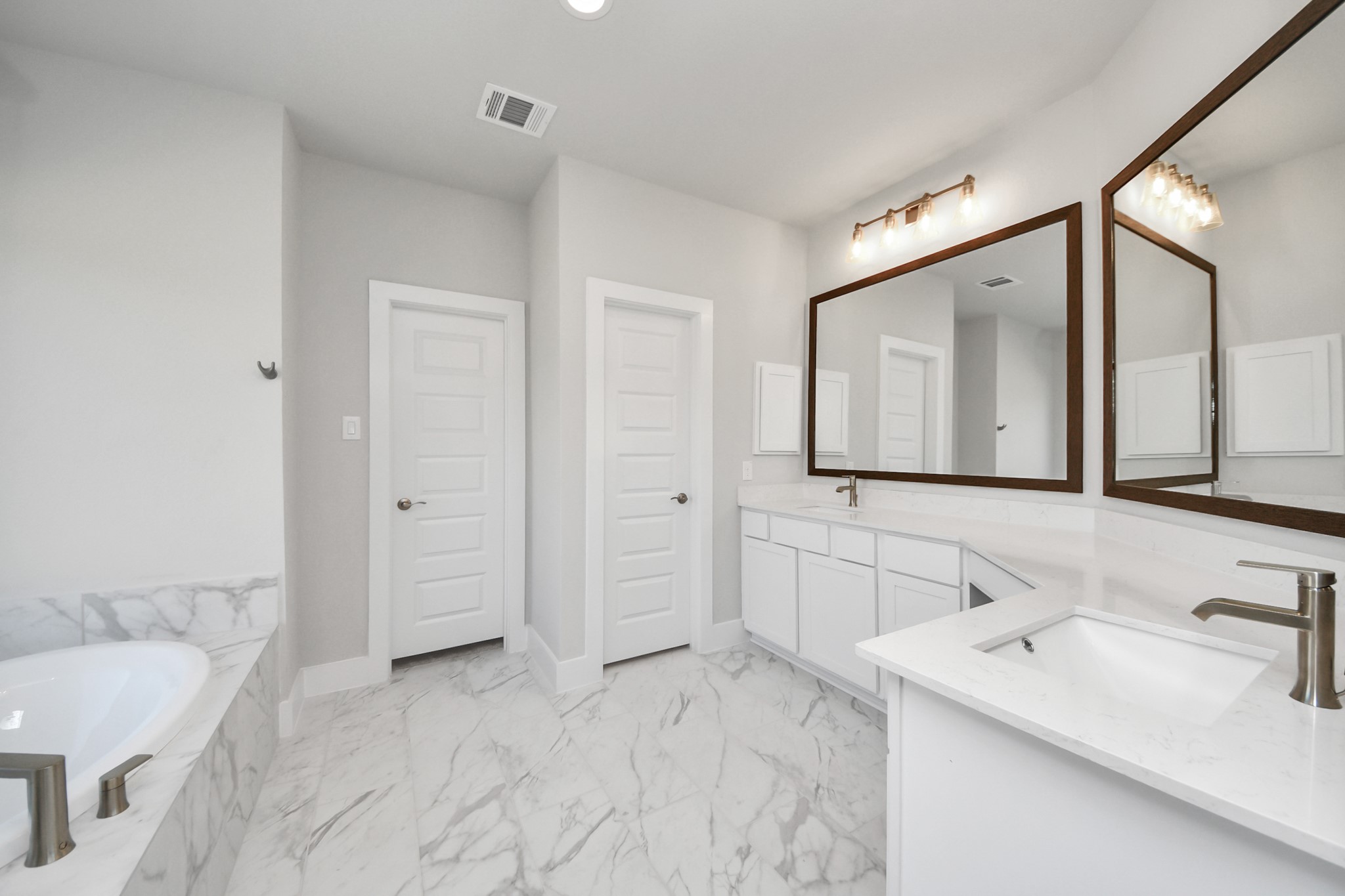 3121 Skerne Spring Dr Spring Spring, TX 77373 - Photo 32 of 44 Escape to a spa-like oasis in this primary bathroom. Enjoy a walk-in shower with tile surround, a separate garden tub with custom detailing, and an elegant vanity featuring light countertops, modern hardware, and beautiful recessed and vanity lights. Experience luxury and relaxation in every detail.