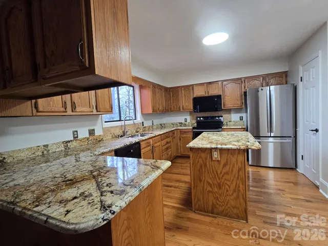 a kitchen with stainless steel appliances wooden cabinets a stove a sink and a microwave