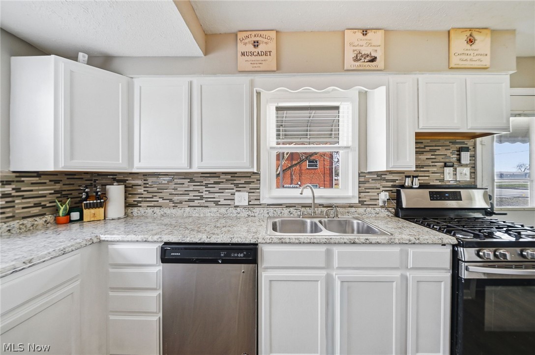 3905 Kent Road Stow, OH 44224 - Photo 18 of 45 Kitchen featuring stainless steel appliances, white cabinetry, backsplash, and light stone counters